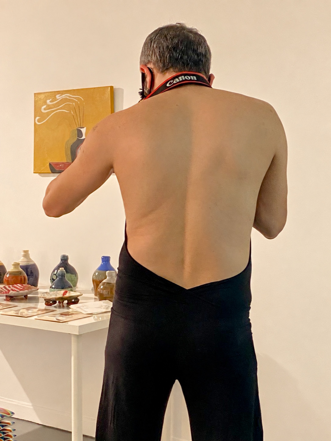 Behdad Esfahbod viewed from behind wearing a Canon camera strap in a gallery